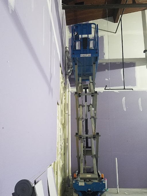 Work in progress - radon vent pipe and fan in commercial building. Scissor lift in use. Radon Safe Homes and Businesses